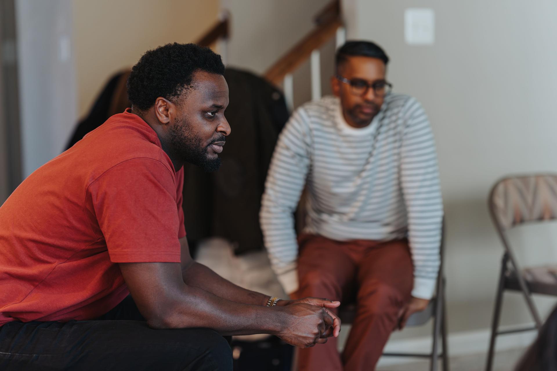 Two young men sit in living room, chatting