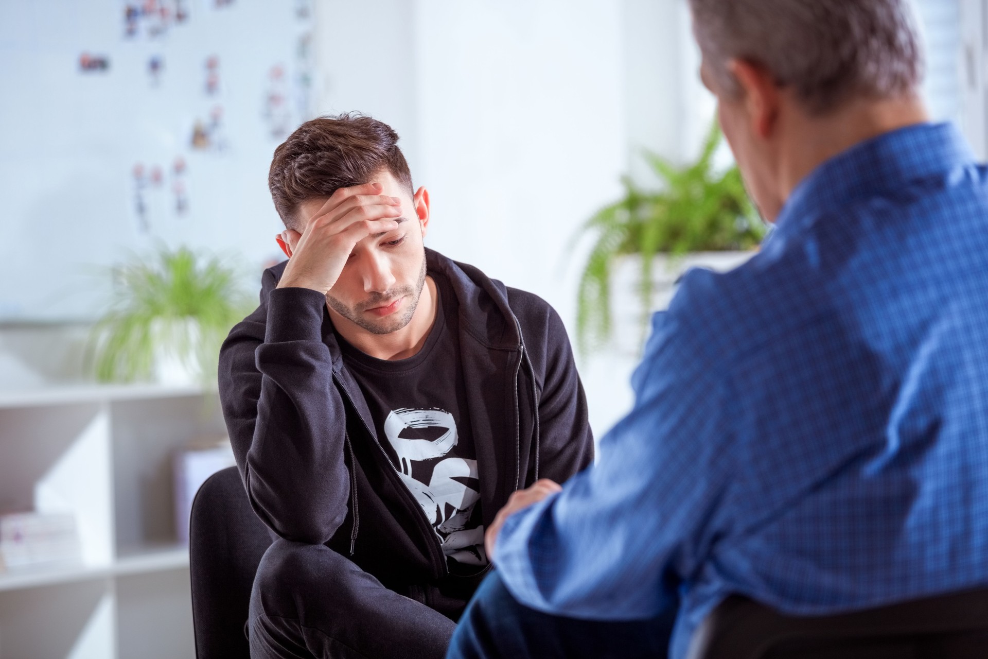 Young depressed man discussing with therapist